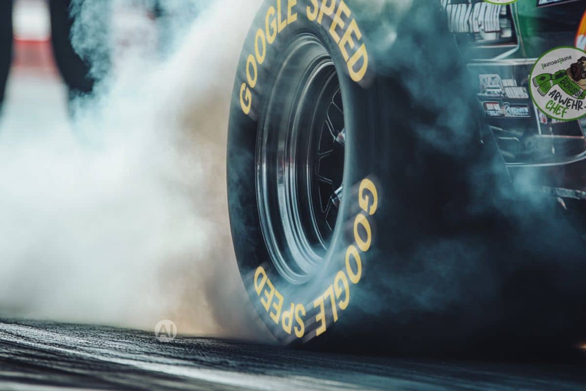 A close-up of a racing tyre performing a burnout on a racetrack – thick plumes of smoke caused by high speed and maximum performance in motor racing.